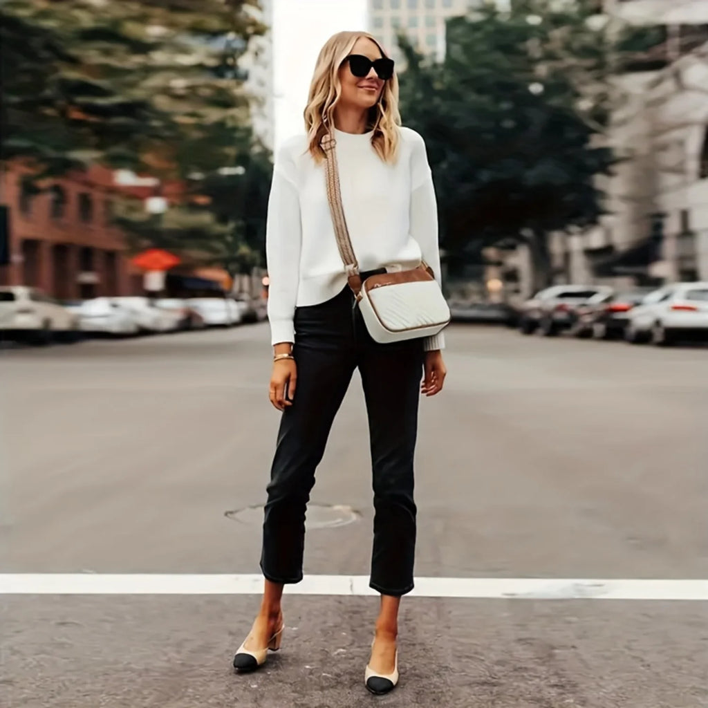 Woman in a white blazer and black pants standing on a city street with vegan leather handbag.